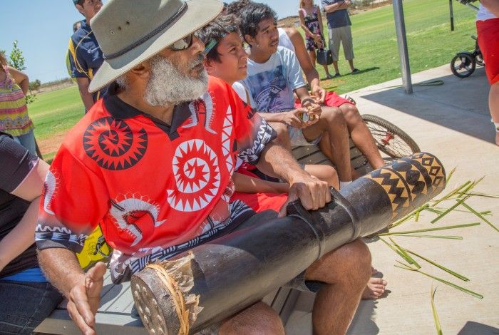 Indigenous man playing music for a group of people