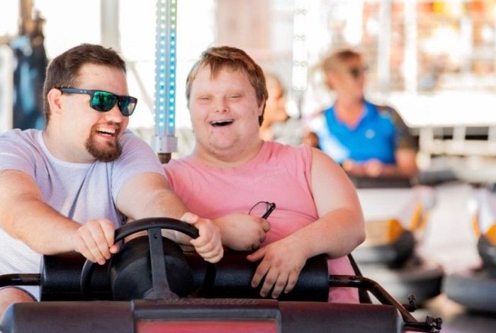 Two people are smiling and enjoying a ride together in a bumper car at an amusement park.