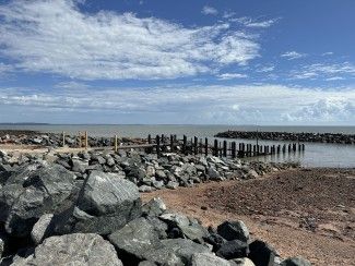 Picture of Back Beach Jetty in daylight surrounded by rocks with blue cloudy sky 